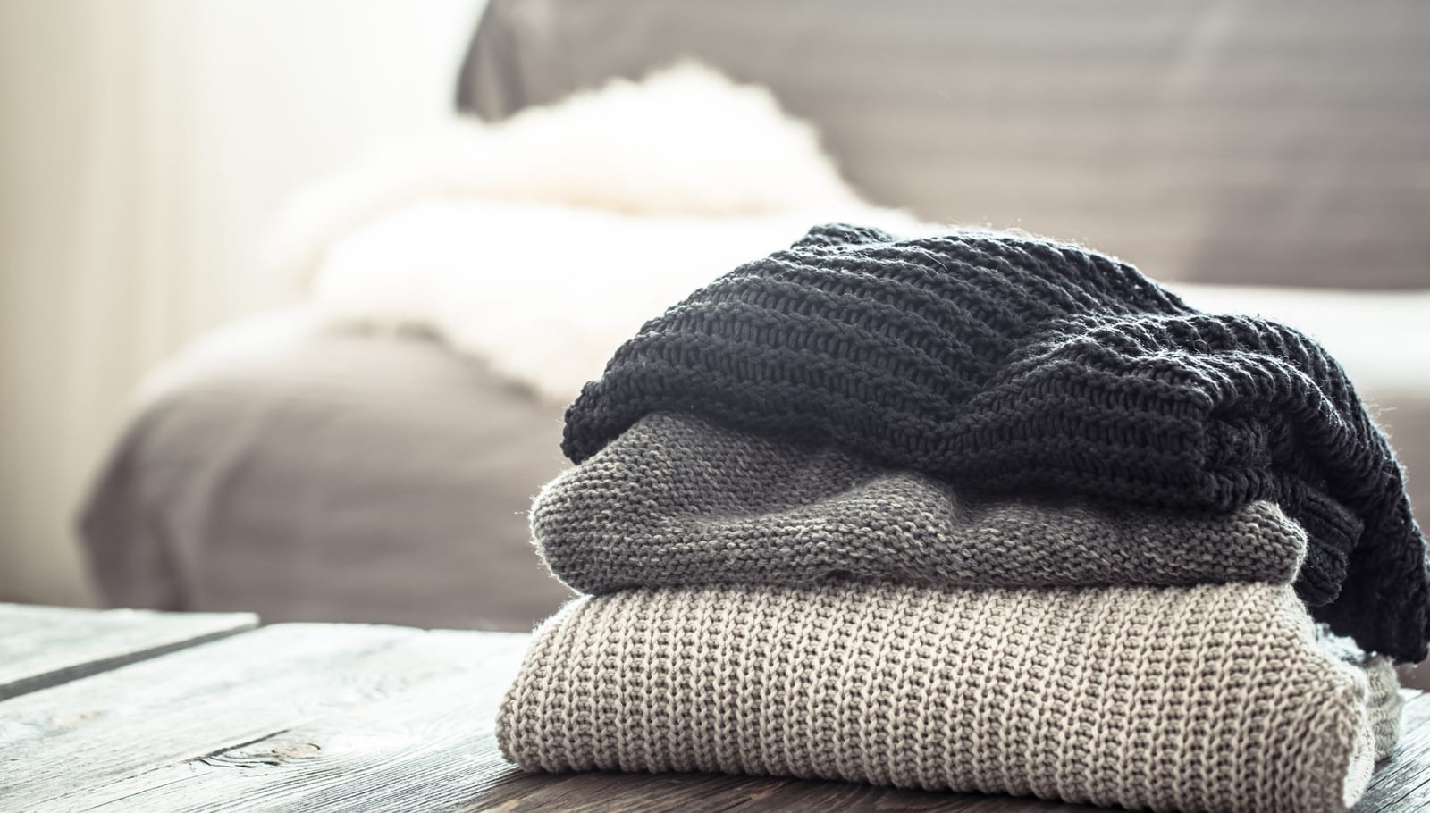 Gestapelte gestrickte Pullover auf einem Holztisch