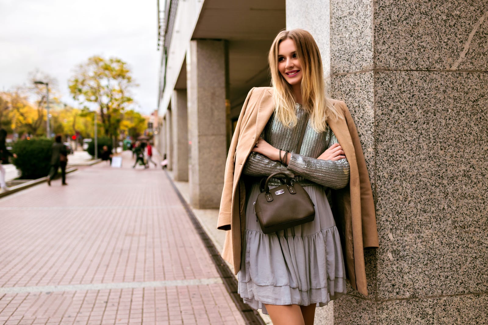 Modische Frau in Seidenkleid, Pullover, Kaschmirmantel und Ledertasche, sanfte Herbstfarben