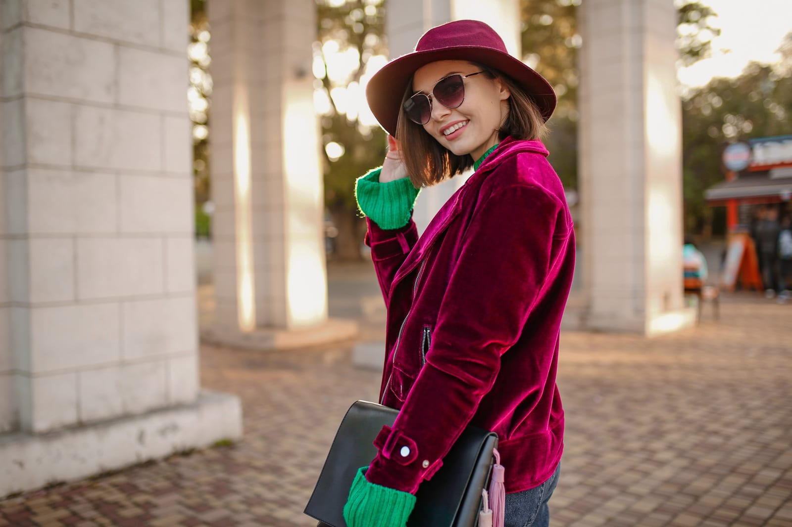 Frau in violetter Samtjacke und Sonnenbrille beim Spaziergang